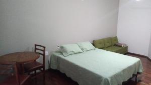 a bedroom with a bed and a table and chair at Hotel Moinho de Pedra in Serra Negra