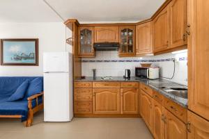 a kitchen with wooden cabinets and a white refrigerator at TAC - Fisherman's Beach Apartment in Albufeira