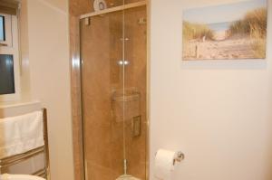 La salle de bains est pourvue d'une douche avec une porte en verre. dans l'établissement Little Birches, à Grimston
