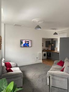 a living room with two couches and a tv on the wall at CLITHEROE TOWN CENTRE MODERN 2 BED APARTMENT in Clitheroe