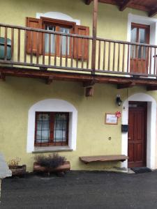 a building with a balcony and a wooden door andwindows at IL Dahù in Pragelato