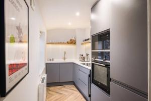 uma cozinha com paredes brancas e electrodomésticos pretos em Great Escapes Oundle Flat 2 em Oundle
