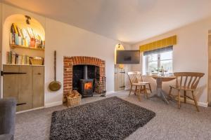 a living room with a table and a fireplace at Lovely Cottage in North Creake