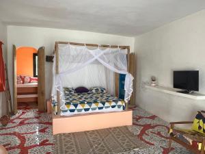 - une chambre avec un lit à baldaquin dans l'établissement Bine Bassile, à Guéréo