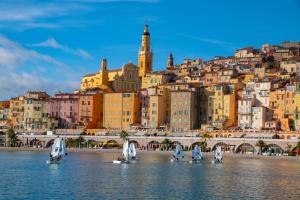 a group of sailboats in the water in front of a city at Hôtel Vendôme Menton - Reouverture in Menton