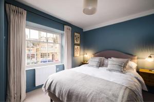 Dormitorio azul con cama y ventana en Great Escapes Oundle Flat 1 en Oundle