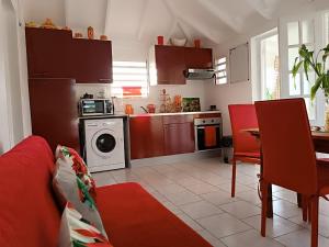a living room with a red couch and a kitchen at La Kaza Tresor - Joli appartement T2 et spa privé in Sainte-Anne
