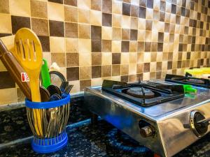 a kitchen counter with a stove and a cup with utensils at Love Lounge in Greater Noida