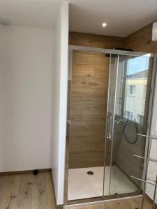 a glass shower in a room with a wooden wall at Superbe Maison avec jardin in Bezannes-les-Reims
