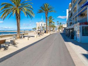 una calle en la playa con palmeras y edificios en Appartement Le Grau-du-Roi, 2 pièces, 4 personnes - FR-1-307-165, en Le Grau-du-Roi