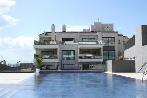 a house with a swimming pool in front of a building at Apartments Sydenbygg Arguineguin in Arguineguín