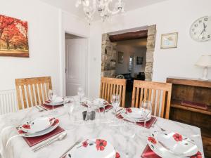 uma sala de jantar com uma mesa com pratos e copos em Halcyon em Moelfre