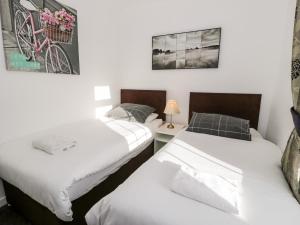 two twin beds in a room with a bike on the wall at Halcyon in Moelfre