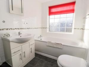 a bathroom with a sink and a tub and a toilet at Halcyon in Moelfre