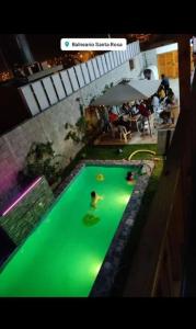 una piscina verde con gente nadando en ella en Villa Alfonso - Casa playa con piscina temperada, en Lima