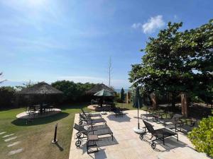 een groep picknicktafels en stoelen met parasols bij Casa pé na areia em praia paradisíaca com piscina frente mar in Balneário Camboriú