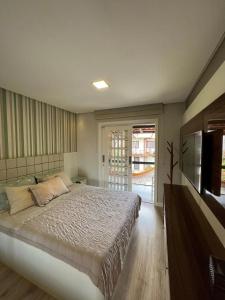 a bedroom with a large bed and a television at Casa pé na areia em praia paradisíaca com piscina frente mar in Balneário Camboriú
