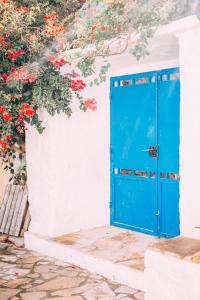 a blue door in a white wall with red flowers at THALASSA New house in Leonidion