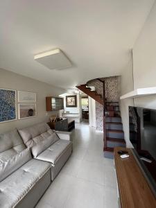 a living room with a couch and a staircase at Casa pé na areia em praia paradisíaca com piscina frente mar in Balneário Camboriú