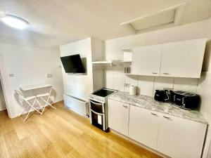 a kitchen with white cabinets and a counter top at Cosy two bedroom apartment,SE13 in London
