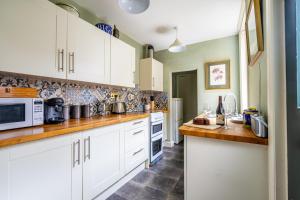 a kitchen with white cabinets and a microwave at The Victorian House in York