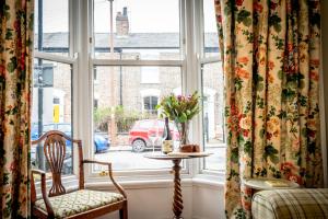 ein Fenster mit einem Tisch und Stühlen sowie einer Blumenvase in der Unterkunft The Victorian House in York