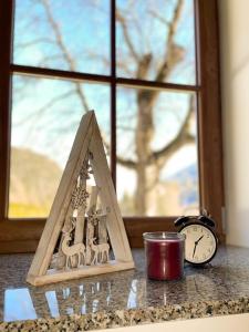 a clock and a candle on a counter next to a window at Apartment House Prezlc in Kranjska Gora