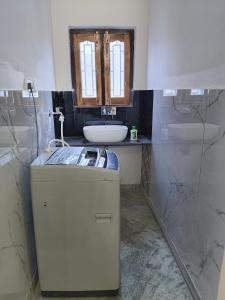 ein Badezimmer mit einem Waschbecken und einem kleinen Kühlschrank in der Unterkunft Pran Prasadam in Ayodhya