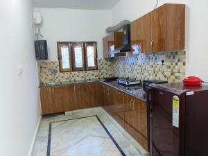 eine Küche mit Holzschränken und einem Kühlschrank in der Unterkunft Pran Prasadam in Ayodhya