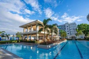 a swimming pool in front of a building with palm trees at Entire 2BR condo 8 Spatial Maa Davao in Davao City
