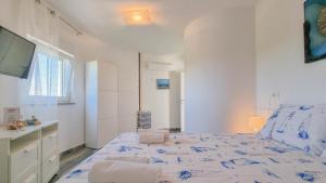 a white bedroom with a bed and a tv at Silos Mare in Novigrad Istria