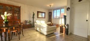 un salon avec un canapé blanc et une table dans l'établissement Konforta : Paisible maison d'été avec grand jardin, à Sainte-Geneviève-des-Bois