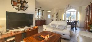 un salon avec une grande télévision à écran plat dans l'établissement Konforta : Paisible maison d'été avec grand jardin, à Sainte-Geneviève-des-Bois