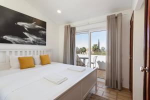 The Albufeira Concierge - Villa Pool & Tennis في Galé: غرفة نوم بسرير ابيض كبير مع مخدات صفراء