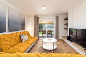 The Albufeira Concierge - Villa Pool & Tennis في Galé: غرفة معيشة مع أريكة صفراء وتلفزيون