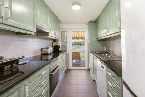 The Albufeira Concierge - Villa Pool & Tennis في Galé: مطبخ مع دواليب خضراء واجهزة بيضاء