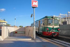 a green and red train pulling into a train station at La Pietra Nera - Etna Home in Catania