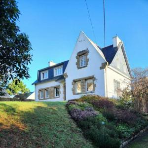 une grande maison blanche sur un champ herbeux dans l'établissement Grande maison en bord de mer, à Concarneau
