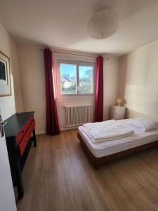 1 dormitorio con 1 cama y una ventana con cortinas rojas en Grande maison en bord de mer, en Concarneau