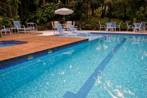 a large swimming pool with chairs and an umbrella at Don Pascual in Rio de Janeiro