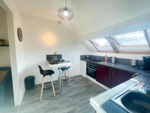uma pequena cozinha com um banco e uma mesa em Le 12 Bis - COSY em Cherbourg en Cotentin