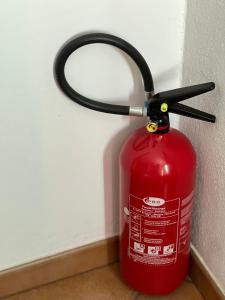 a red fire hydrant with a hose attached to a wall at The Comfy Apartment in Ponte Capriasca