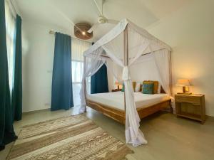 a bedroom with a canopy bed with blue curtains at Ocean Boutique Hotel in Pingwe