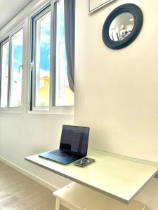 a laptop sitting on a desk in a room with windows at Cristalia,Roof terrace in city center, Garage, Netflix 75inch TV in Funchal