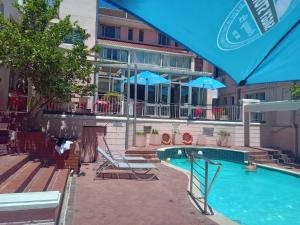 a swimming pool with chairs and umbrellas next to a building at Auberge Gardens in Cape Town