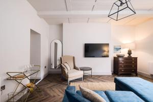 un salon avec un canapé bleu et une télévision dans l'établissement Great Escapes Oundle Flat 3, à Oundle