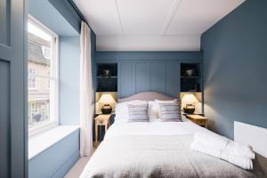 um quarto com paredes azuis e uma cama com almofadas em Great Escapes Oundle Flat 3 em Oundle