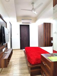 sypialnia z czerwonym łóżkiem, biurkiem i telewizorem w obiekcie Hotel comfort inn w mieście Calangute
