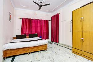 a bedroom with a bed and red curtains at OYO Hotel Trishakti Homestay in Lucknow