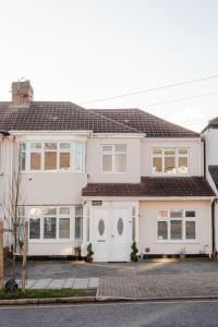 uma casa branca com um telhado castanho em Apple House Wembley em Barnet